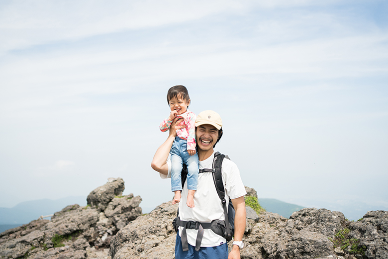 山頂で笑う親子の写真